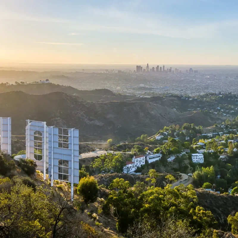 Scenic view of hillside luxury homes with the Hollywood sign and downtown Los Angeles skyline at sunset